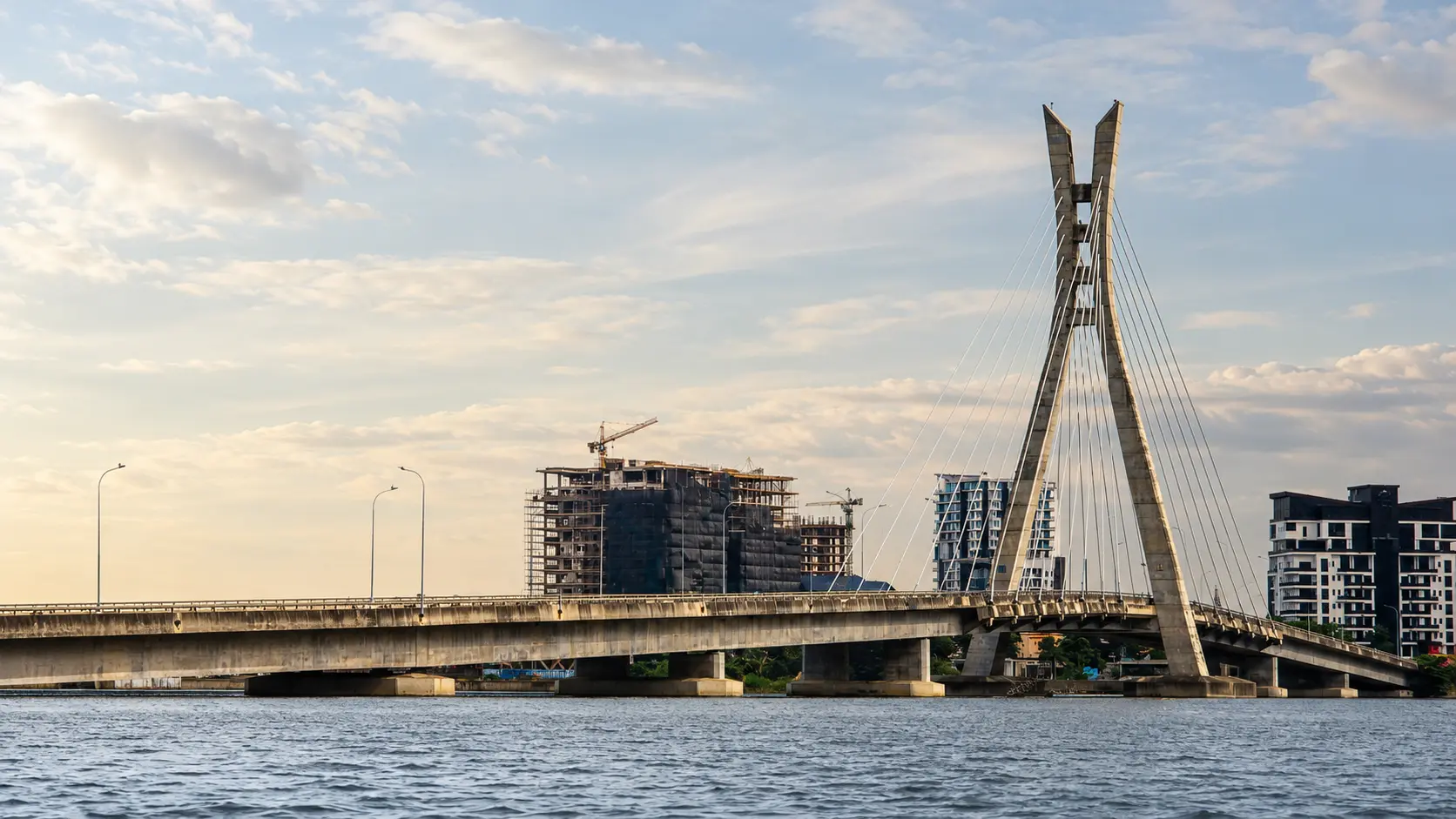 Lagos skyline and bridge infrastructure at dusk with buildings under construction.