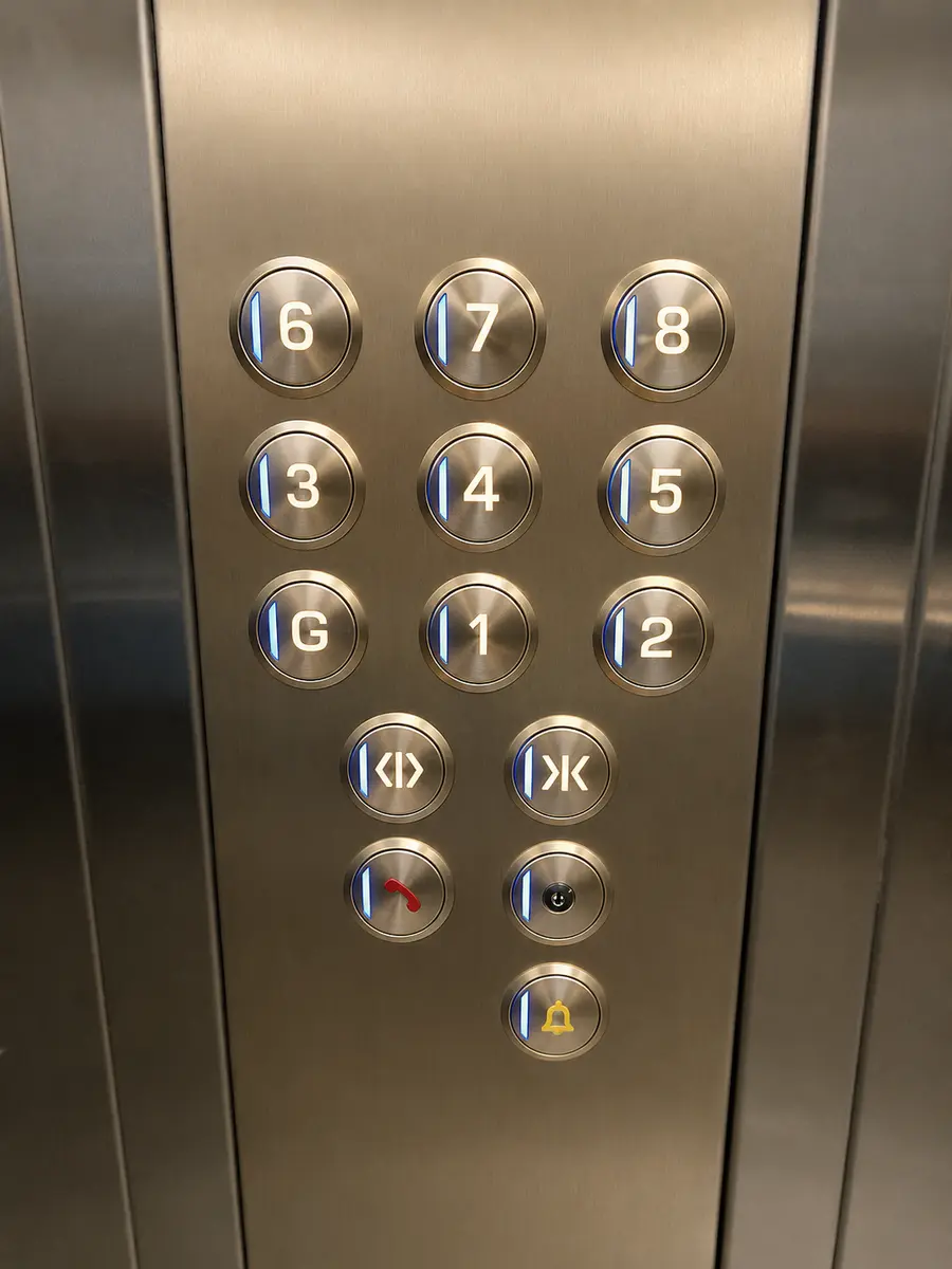 Champagne gold lift car operating panel with blue illuminated buttons.